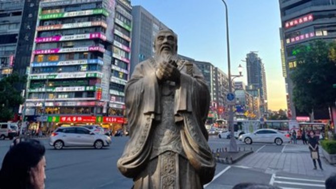 Chinesische Statue im Vordergrund auf belebtem modernen Platz
