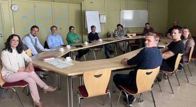 Die Teilnehmer*innen sitzen am Konferenztisch in der Bibliothek