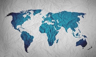 Eine gemalte Weltkarte. Die Kontinente sind in blauer Farbe, der Hintergrund ist als verknittertes Papier dargestellt.