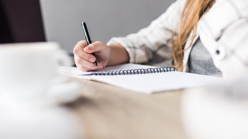 Frau schreibt in ein Notizbuch