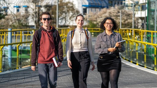 Drei Studierende laufen über den Campus