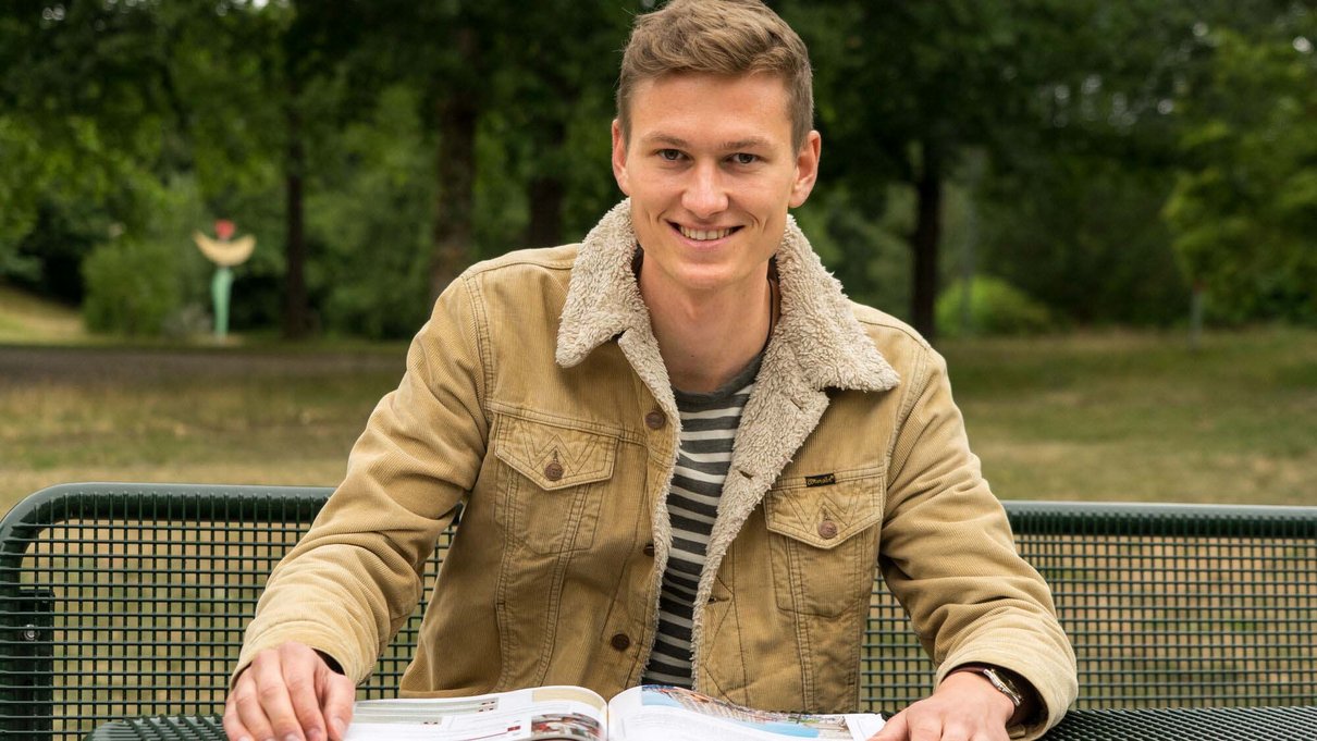 Student mit Buch im Learning Garden