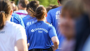 Läuferin von hinten. T-Shirt mit Aufschrift "Universität Trier".