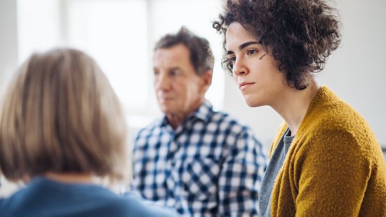 Gesprächsrunde mit zwei Frauen und einem Mann, eine Frau hört zu.