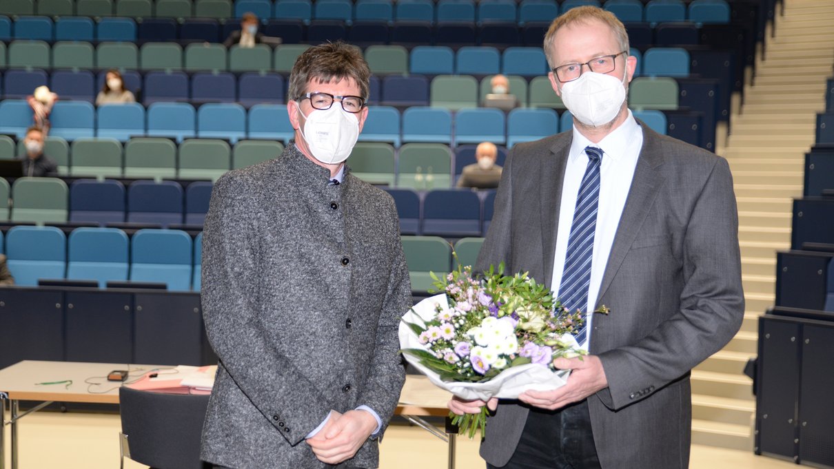 Mit einem Blumenstrauß gratuliert Universitätspräsident Prof. Dr. Michael Jäckel (links) Prof. Dr. Torsten Mattern zur Wahl.