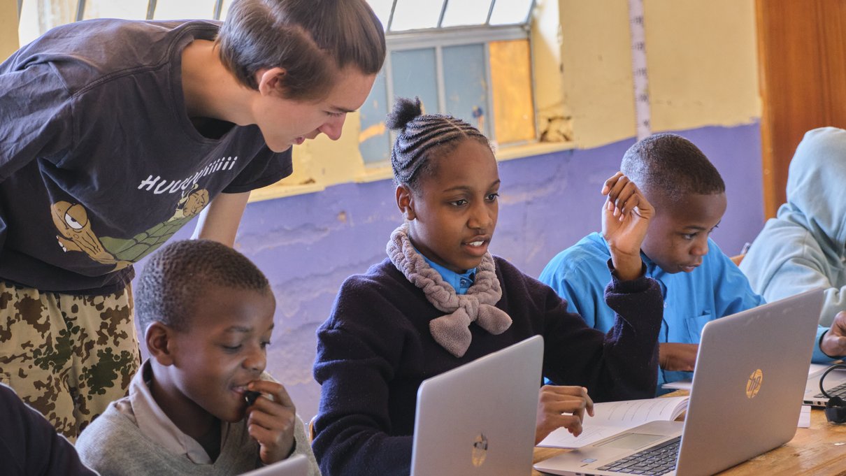 Ein Informatikstudent erklärt einer Schulklasse in Namibia etwas am Laptop