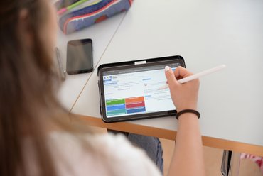 Person sitzt vor einem Tablet, auf dem die Homepage Porta zu sehen ist.