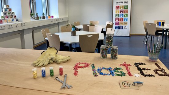 [Translate to Englisch:] Plast.Ed geschrieben mit alten Plastikstücken auf einem Tisch