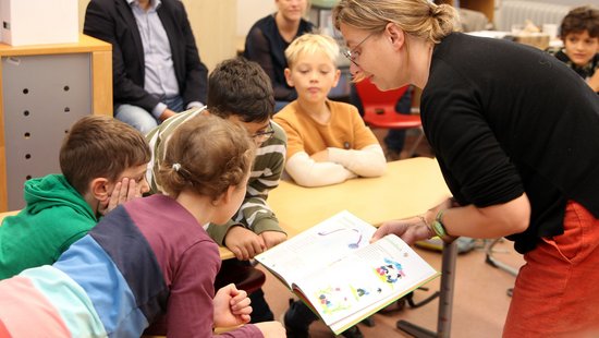 Projektkoordinatorin Sabine Desoye zeigt Schülerinnen und Schüler der Matthias Grundschule Trier die Bilderbücher. Foto: Björn Pazen
