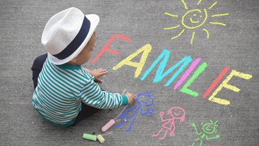 Kind malt mit Straßenkreide Familie
