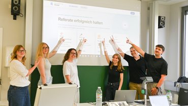 Studierende zeigen auf eine Referatelernumgebung