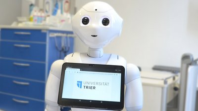 Roboter Pepper mit Tablet, das das Uni Trier Logo anzeigt
