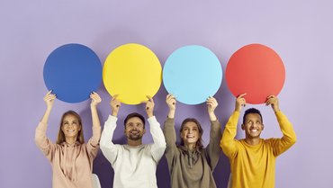 4 junge Erwachsene halten vor einem violetten Hintergrund jeweils einen andersfarbigen Papierkreis hoch