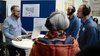 Wissenschaftler macht Hörexperiment mit drei Besuchern, die Kopfhörer tragen