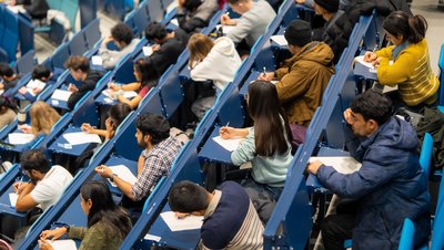 Studierende sitzen über einer Klausur im Audimax