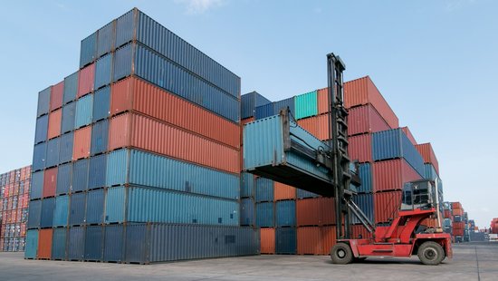 Blaue und rote Container werden in einem Hafen transportiert und gestapelt
