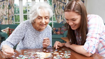 Eine Studentin macht mit einer Senioren ein Puzzle. Foto: Colourbox.de