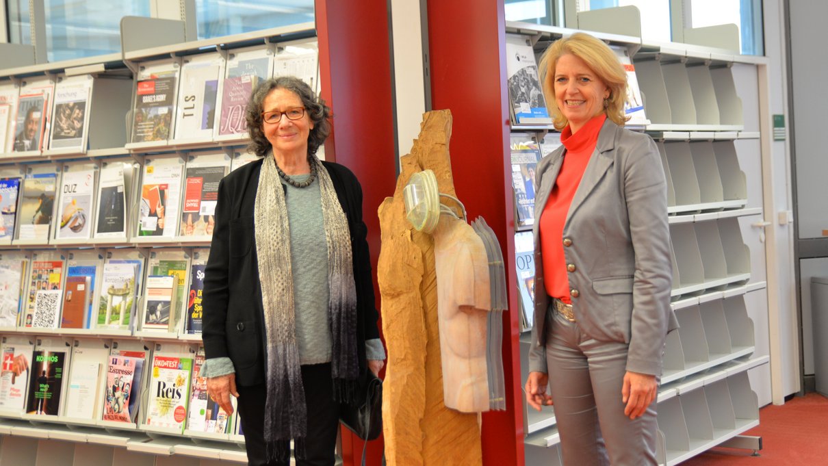 Gisela Siepmann-Wéber, die die Universität Trier mit einer Skulptur ihres verstorbenen Mannes Pierre Wéber beschenkte, und Universitätspräsidentin Prof. Dr. Eva Martha Eckkrammer freuen sich über das neue Kunstwerk in der Bibliothek.