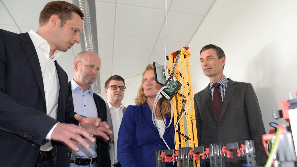 Patrick Klein, Prof. Dr. Axel Kalenborn, Lukas Malburg und Prof. Dr. Georg Müller-Fürstenberger (von links), Vizepräsident der Universität Trier, informieren Staatssekretärin Heike Raab am Beispiel eines Fischertechnik-Modells.