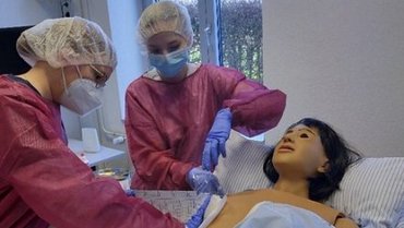 Zwei Studierende führen eine sterile Wundversorgung am Simulator im SkillsLab durch