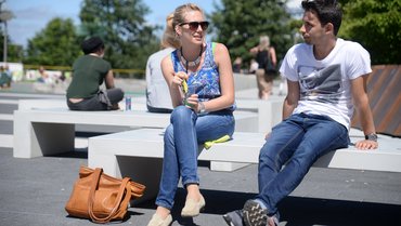 Zwei Studierende auf dem Campus im Sommer mit Cocktail in der Hand