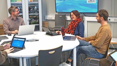 4 Personen sitzen mit Laptops am Tisch