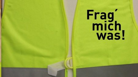 Gelbe Sicherheitsweste mit Aufdruck "Frag mich was"