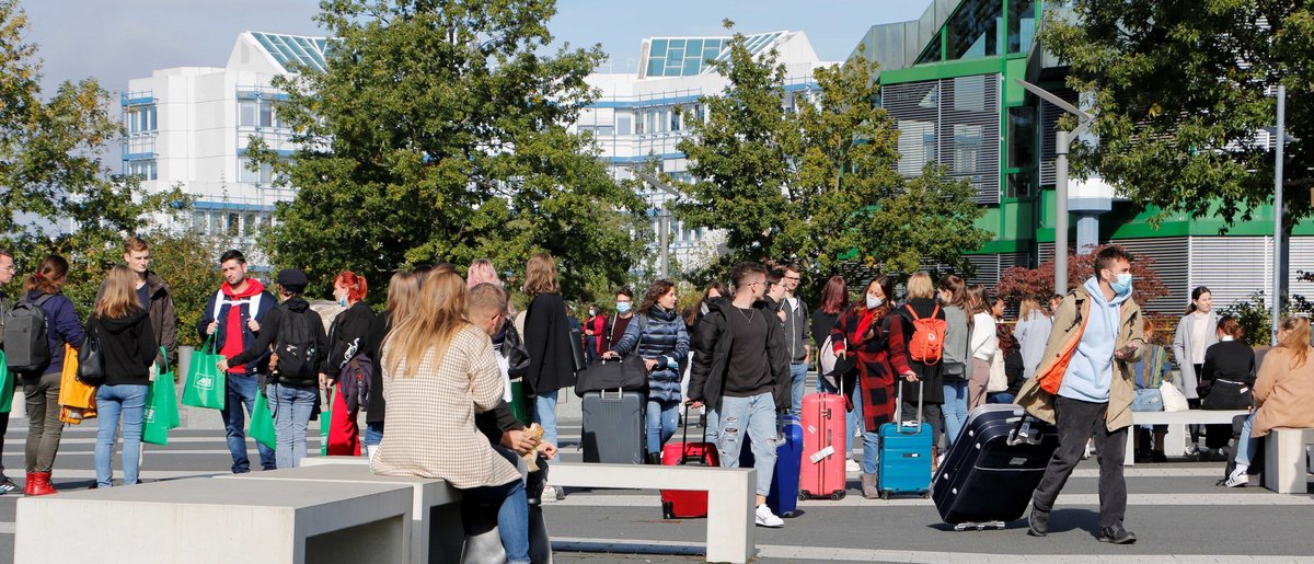 Menschen laufen auf dem Forum der Universität, manche mit Koffern.